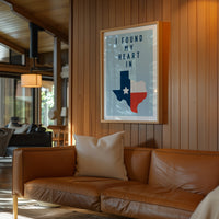 a cozy living room with a brown leather couch, a framed poster of the state of Texas, and a wooden wall.