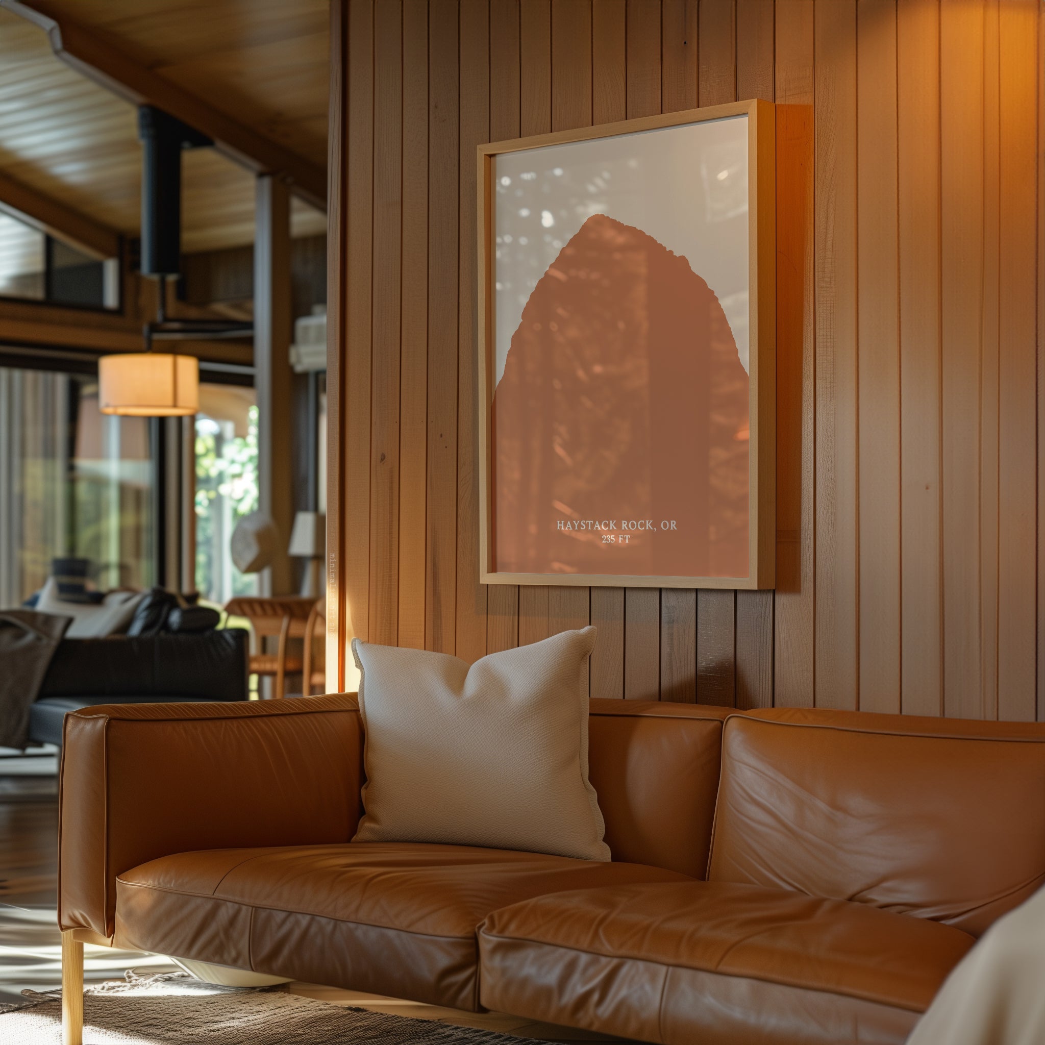 a cozy living room with a brown leather sofa, a framed picture of a mountain, and a wooden wall.