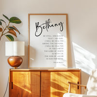 May include: A framed print with the name "Bethany" in elegant script. Below, inspirational text from Psalm 46:10-11 is displayed in a clean, modern font. The artwork is set against a white background.