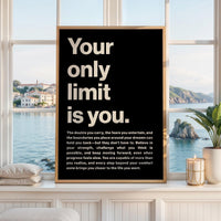 May include: A rectangular wall art print in a light wood frame featuring a black background with large, bold, cream-colored text that reads: Your only limit is you. Below this, a smaller paragraph of text provides an inspirational message.
