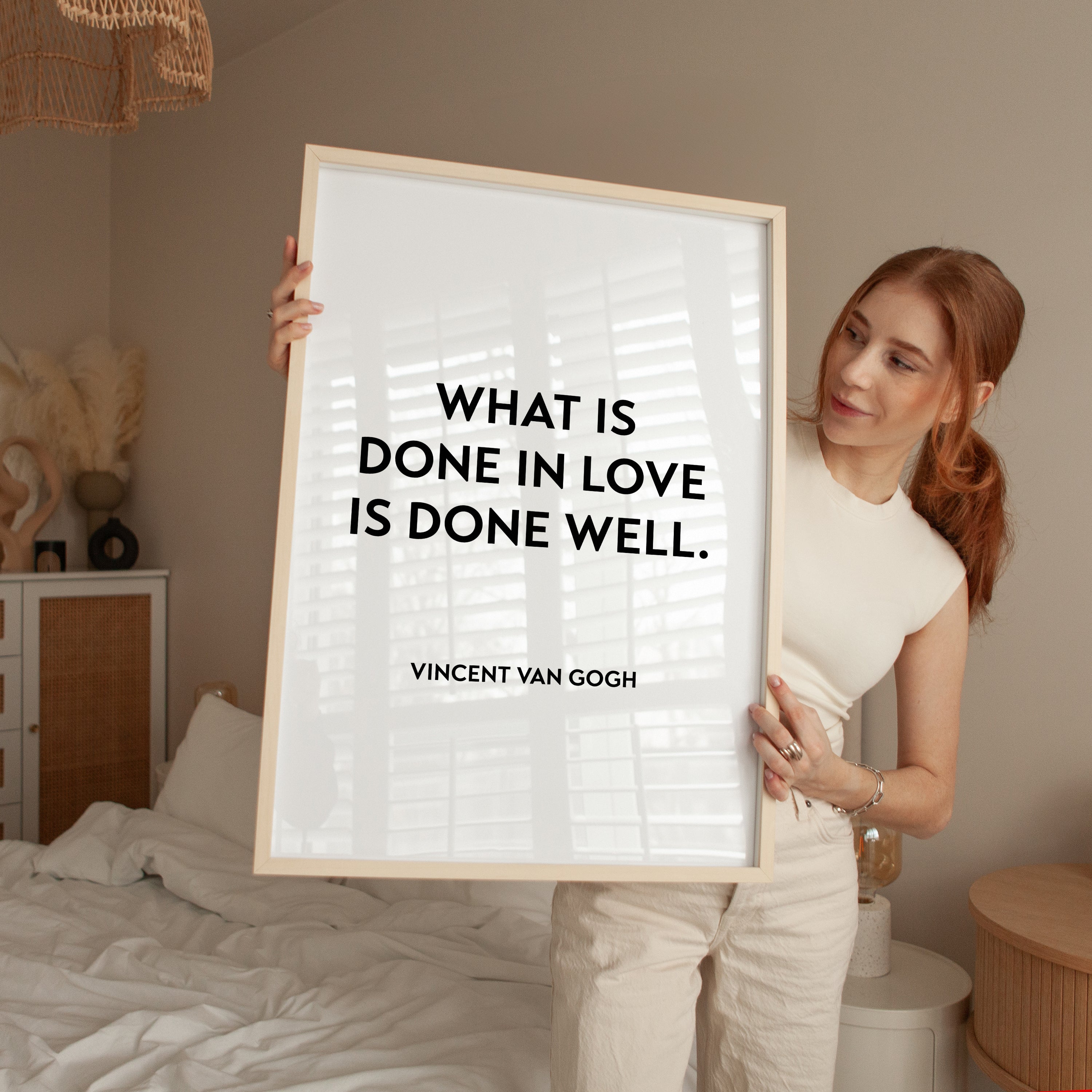 A woman holding a framed poster with the quote "What is done in love is done well." by Vincent Van Gogh.
