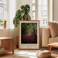 A framed photograph of a forest path with fallen leaves is displayed in a living room, accompanied by a quote about nature and the importance of walking with nature.