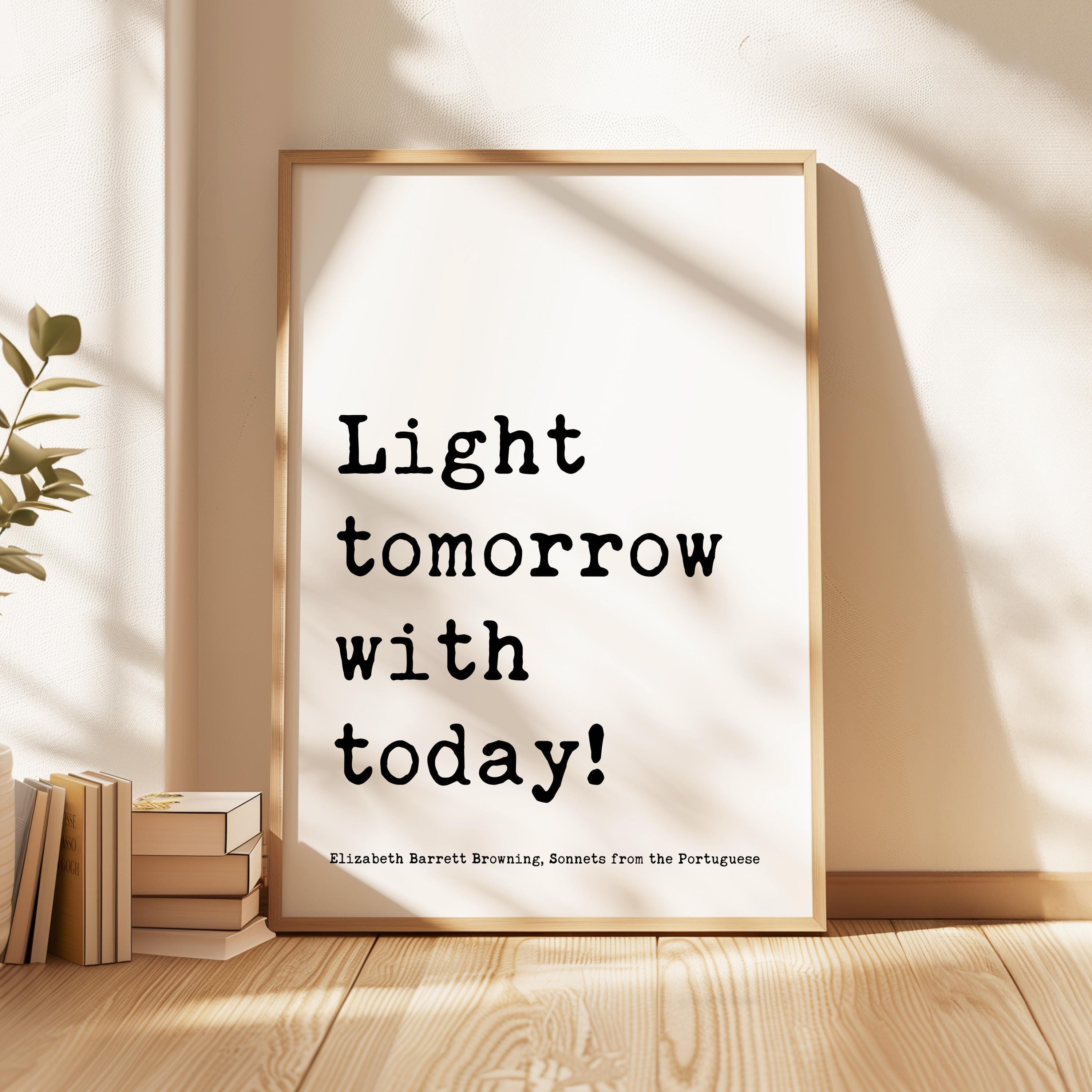 May include: A framed print with a white background and black text that reads 'Light tomorrow with today!' The text is in a typewriter font. Below the text is a smaller line of text that reads 'Elizabeth Barrett Browning, Sonnets from the Portuguese'.