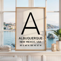May include: A rectangular wall art print in a light wood frame featuring a large black letter A centered at the top. Below the letter, the text reads ALBUQUERQUE, NEW MEXICO, USA, followed by the coordinates 35° 5' 46" N 106° 40' 12" W.