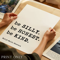 A person's hands holding a large sheet of paper with the quote "be SILLY. be HONEST. be KIND." printed on it.