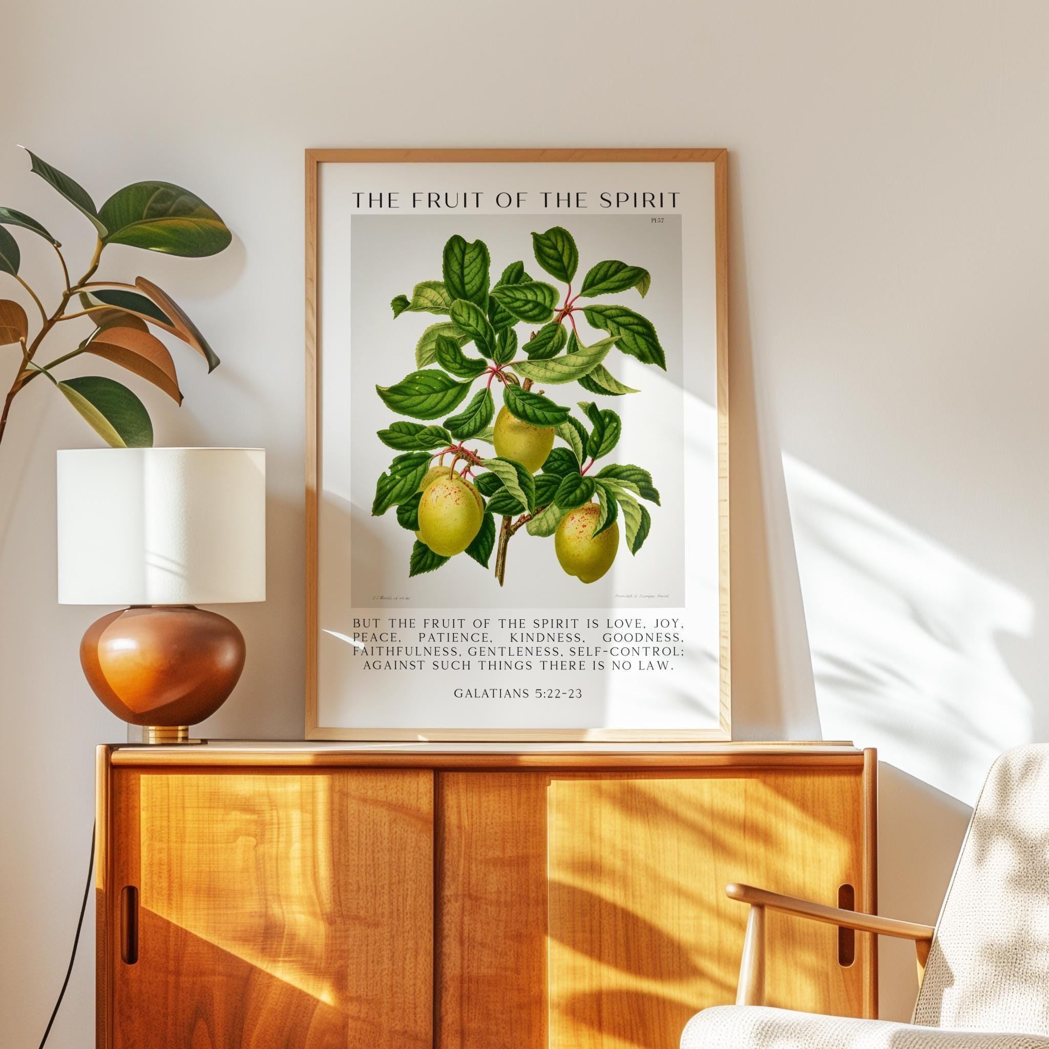 May include: A framed botanical print titled "The Fruit of the Spirit." The artwork features a detailed illustration of a fruit-bearing branch with green leaves and yellow-green fruit. Text from Galatians 5:22-23 is below the image.
