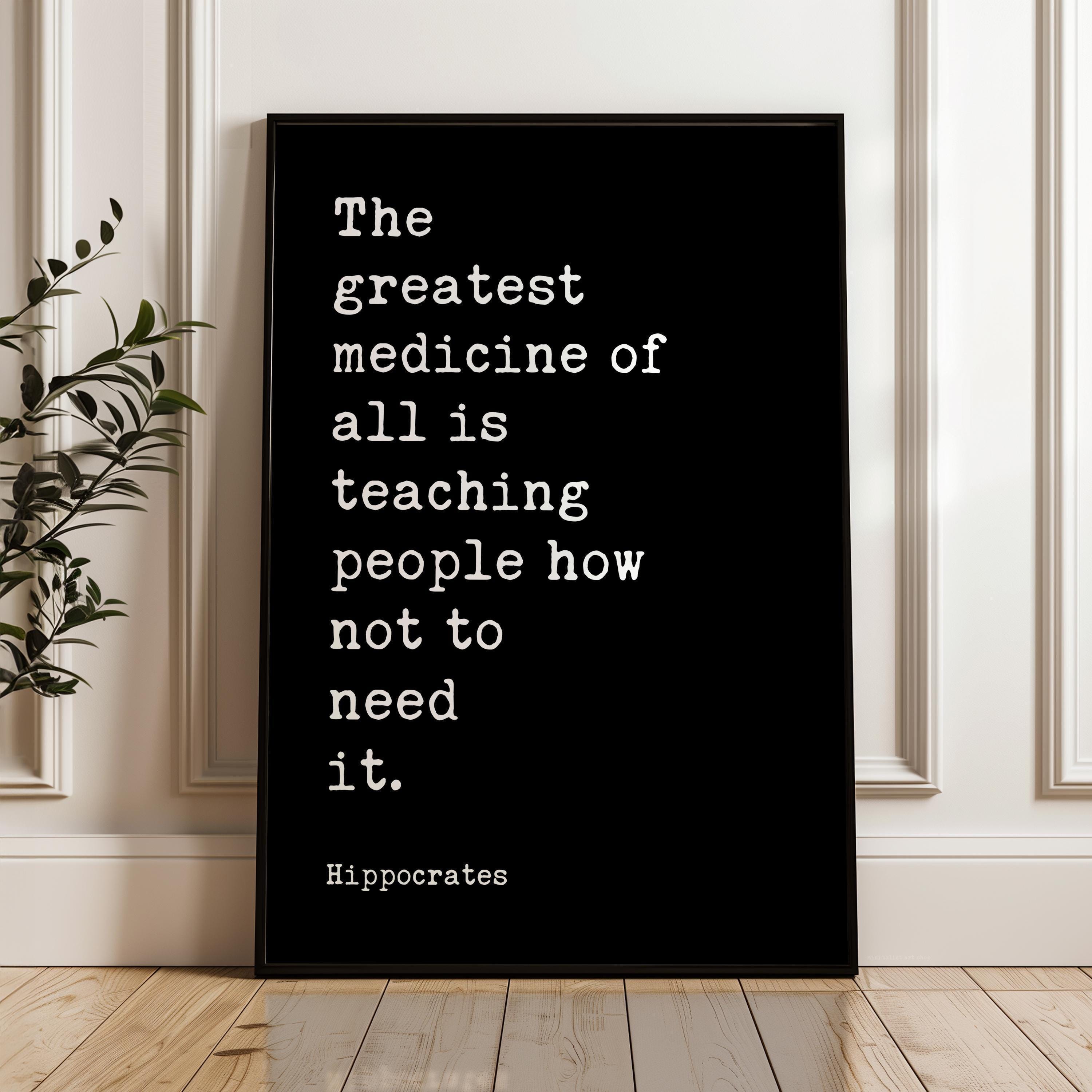 May include: Black framed print with white text. The text reads: "The greatest medicine of all is teaching people how not to need it." The quote is attributed to Hippocrates. The print is displayed on a wooden floor.