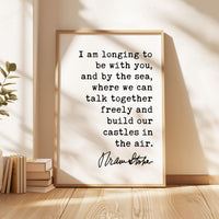 May include: A framed print with a light wood frame. The print features black text on a white background. The text reads, "I am longing to be with you, and by the sea, where we can talk together freely and build our castles in the air."