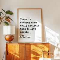 a framed quote by Vincent Van Gogh, which reads "There is nothing more truly artistic than to love people." The quote is displayed on a wooden cabinet or dresser, with a lamp and a plant nearby.