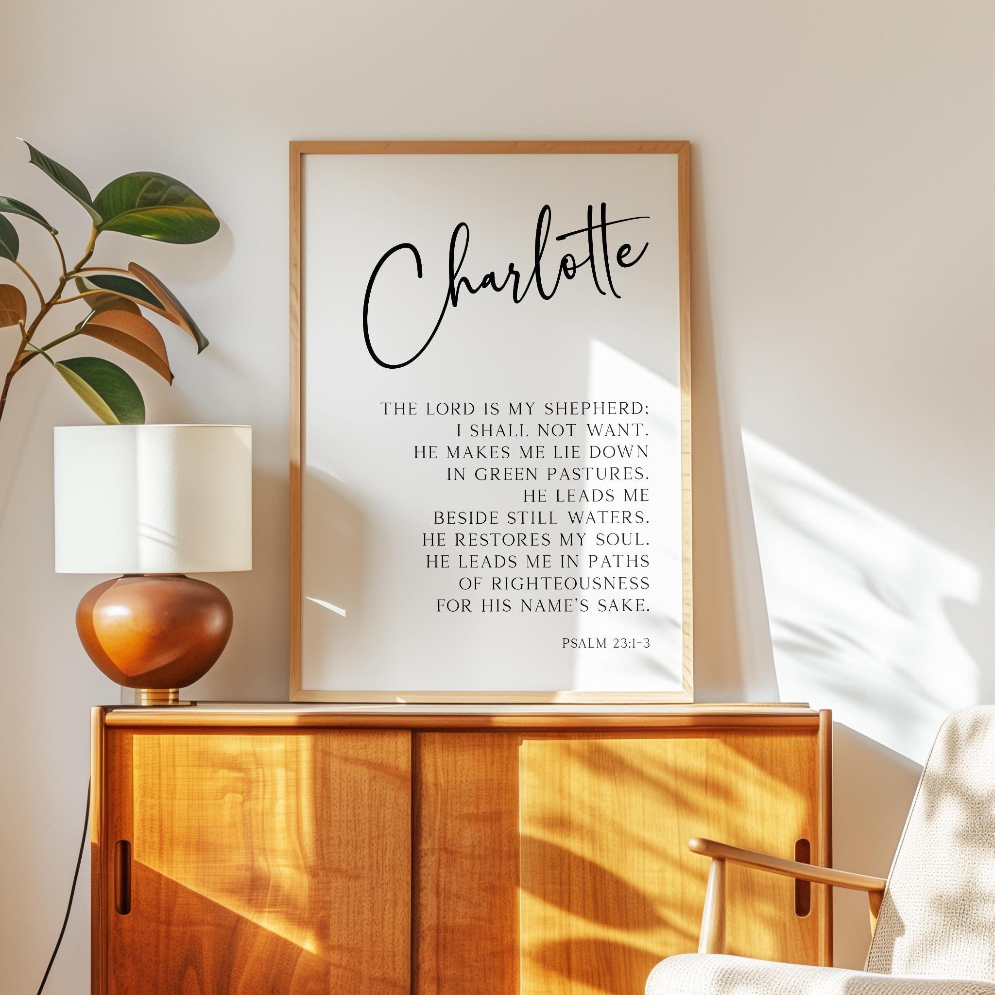 a framed Bible verse titled "Charlotte" with a wooden cabinet and a lamp in the background.
