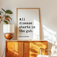 a wooden cabinet with a lamp on top, and a framed quote by Hippocrates that reads "All disease starts in the gut."