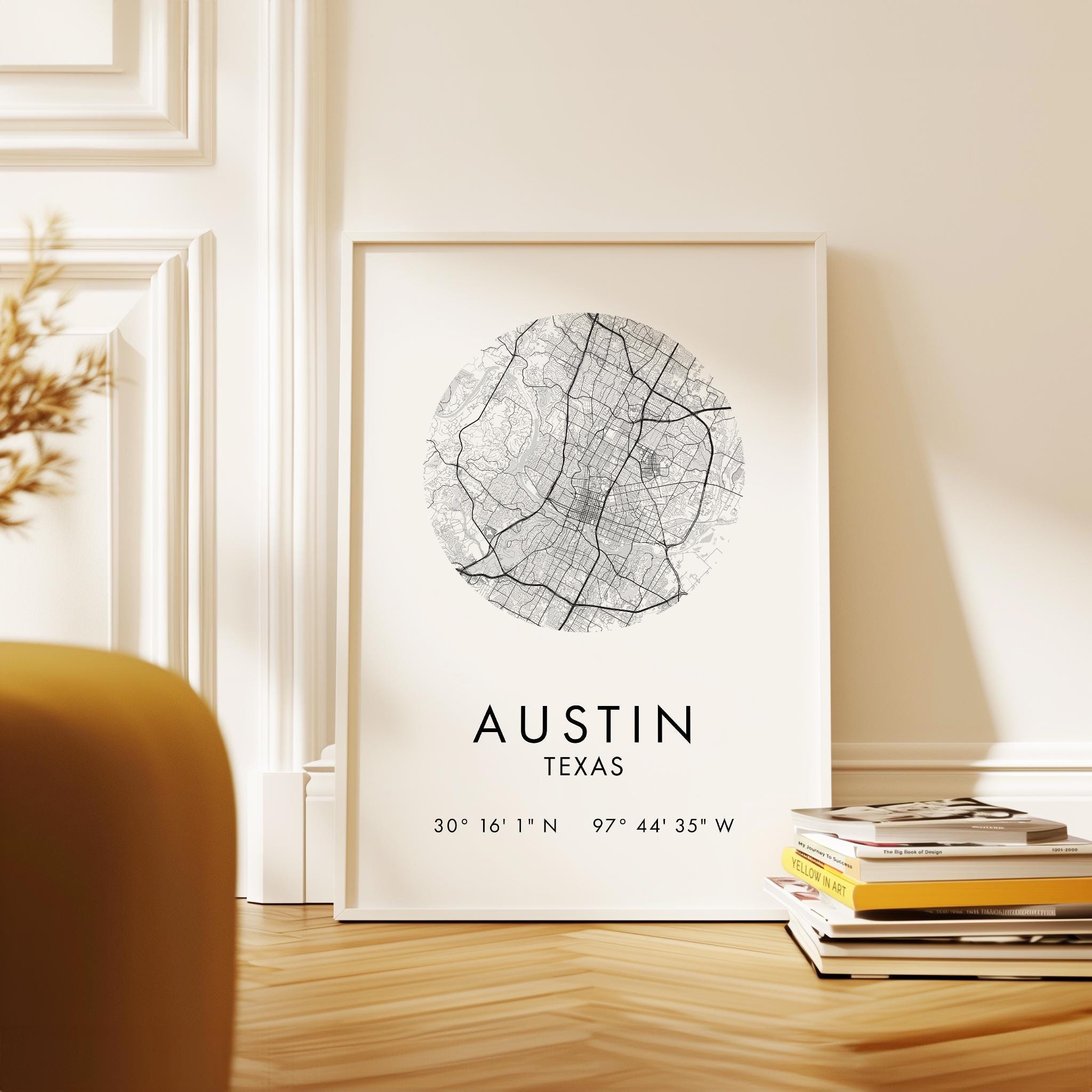 A framed map of Austin, Texas, with the city's location and surrounding area, placed on a wooden floor next to a stack of books.