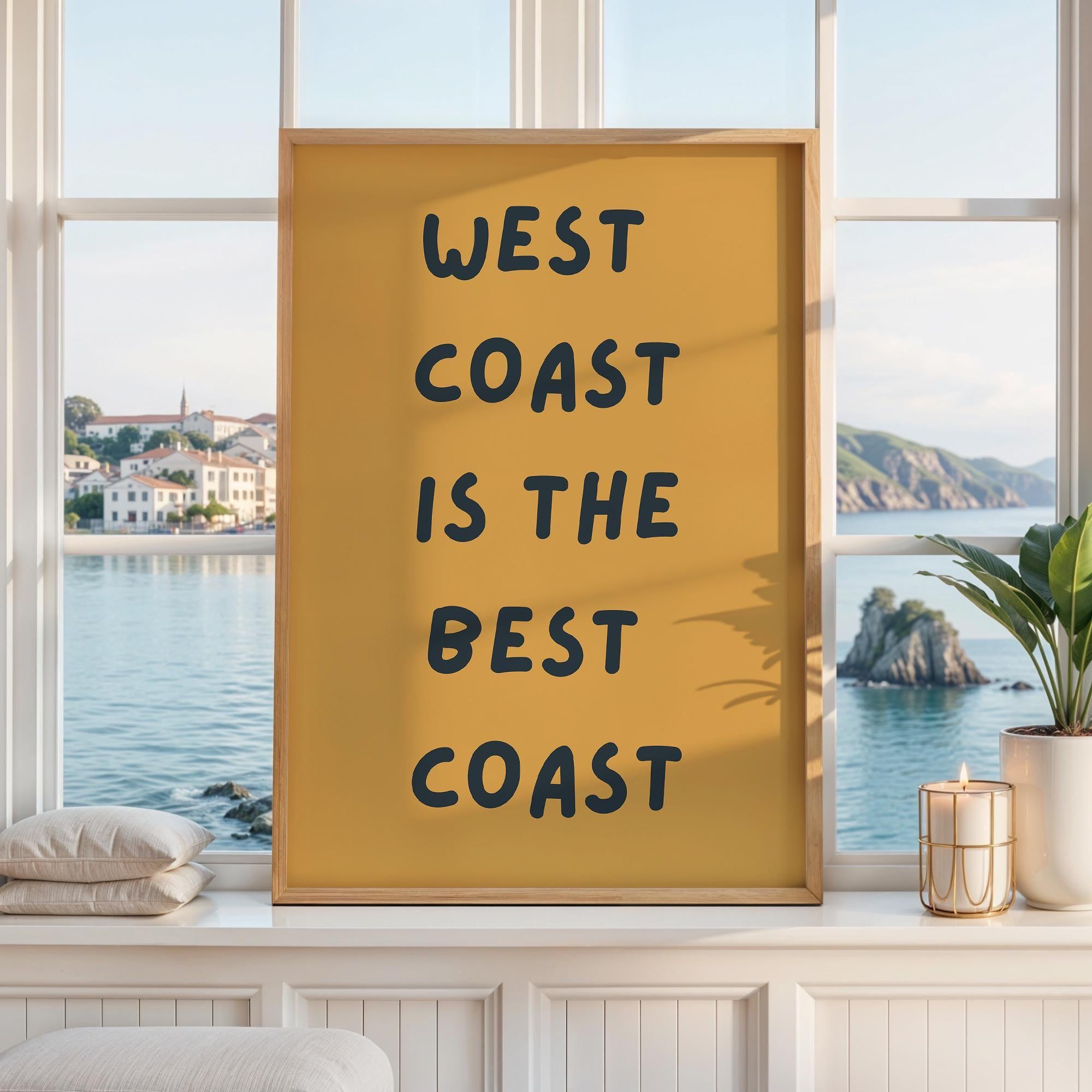 May include: A rectangular wall art print in a light wood frame featuring a mustard yellow background with the black text WEST COAST IS THE BEST COAST written in a bold, rounded, sans-serif font centered on the vertical surface of the print.