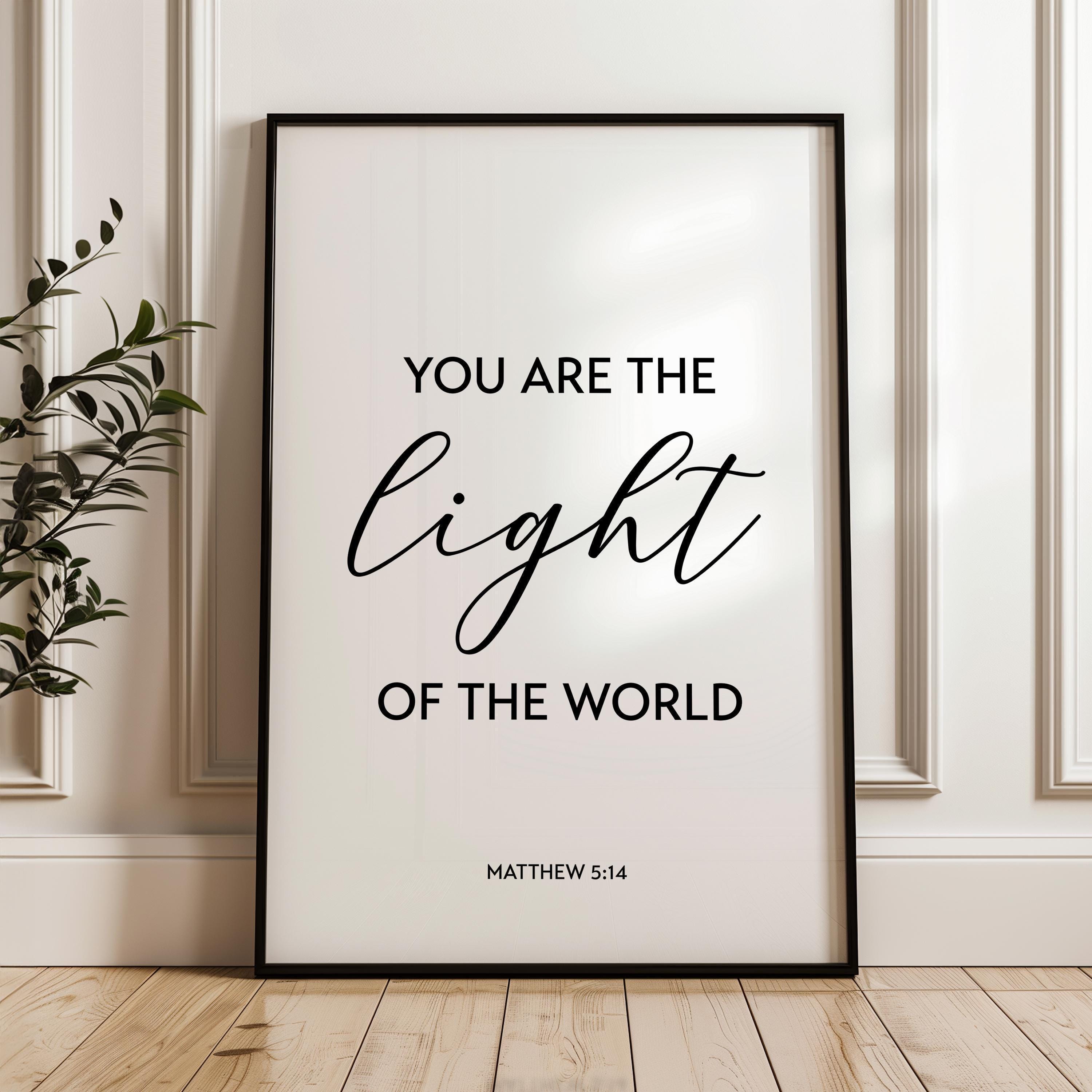 May include: A black framed poster with white background and black text. The text reads 'You are the light of the world' with 'Matthew 5:14' below.
