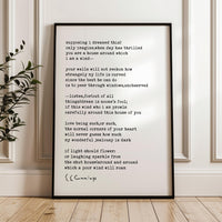 a framed text on a wall, with a plant in the background.