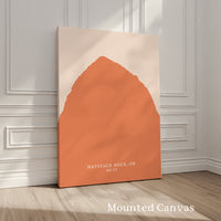 a large canvas print of a mountain range, with a prominent orange shape in the center. The text "HAYSTACK ROCK, OR" is visible, indicating the location or subject of the artwork.