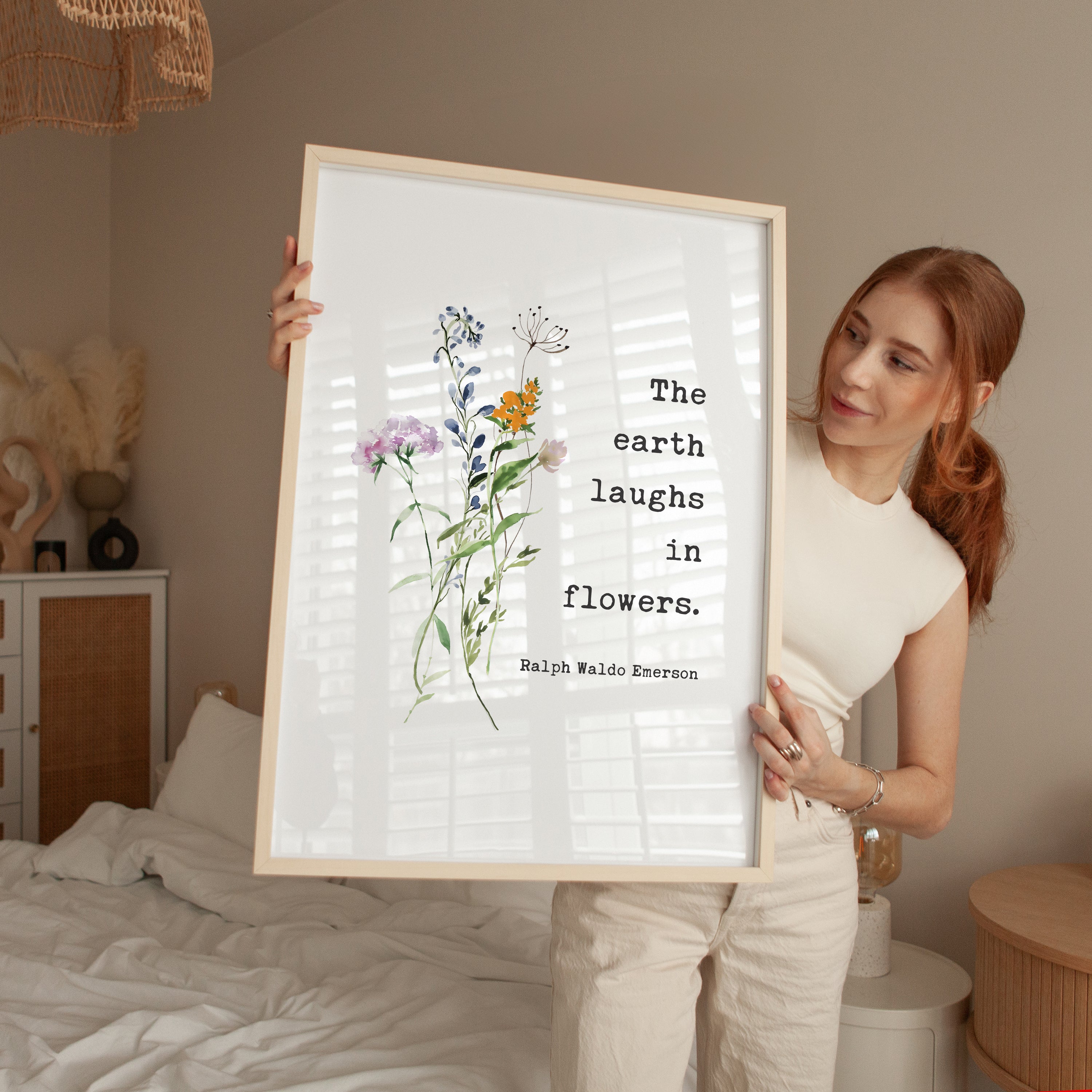 A woman holding a framed print with a quote about flowers and the earth.