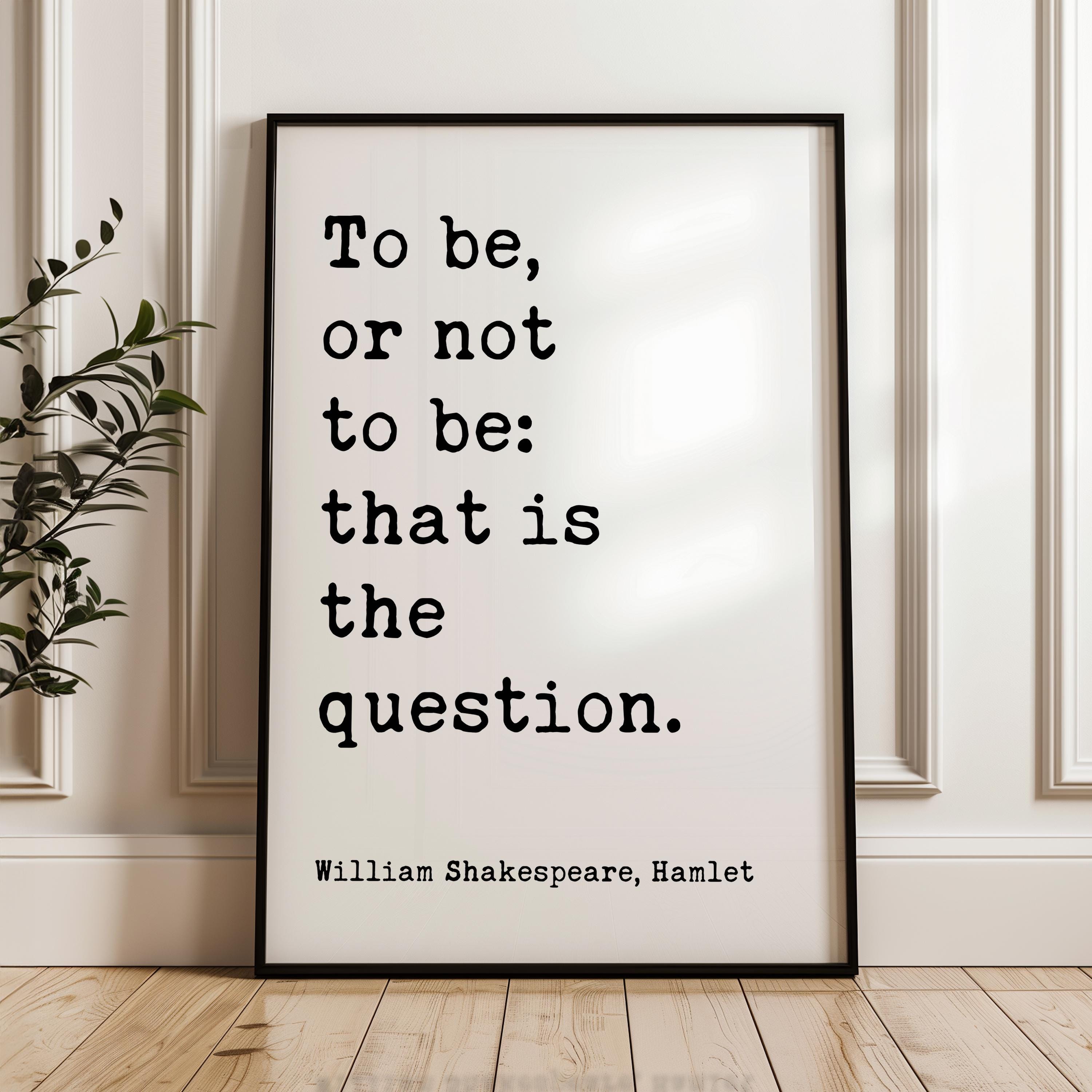 A framed quote by William Shakespeare, "To be, or not to be: that is the question," is displayed on a wooden floor against a white wall.