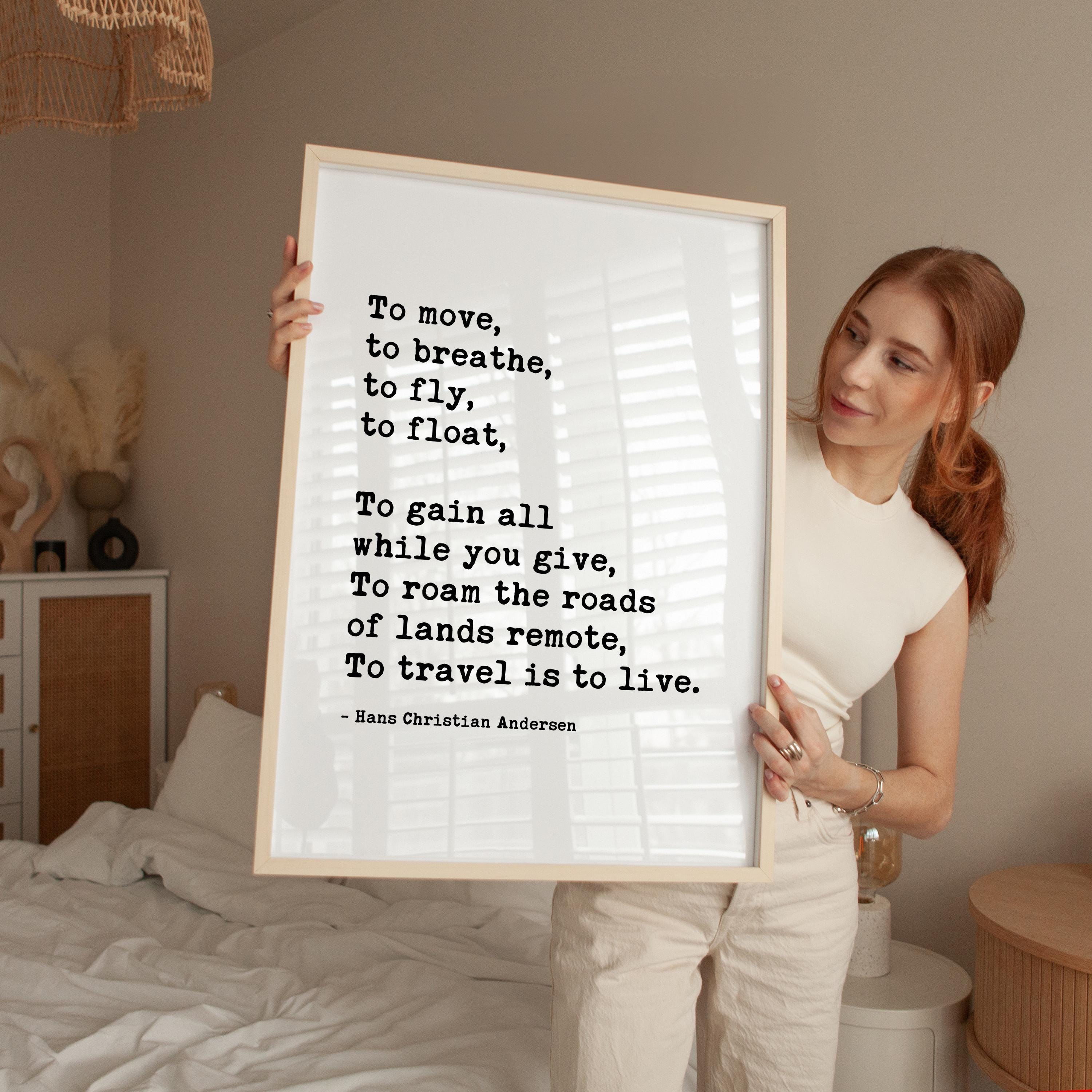 A woman holding a framed quote in a bedroom.