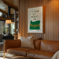 a cozy living room with a brown leather couch, a framed poster of Oregon, and a wooden wall.