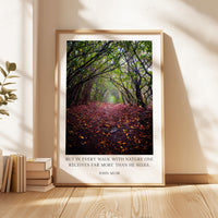 A framed photograph of a forest path covered in fallen leaves, with a quote attributed to John Muir superimposed on the image.