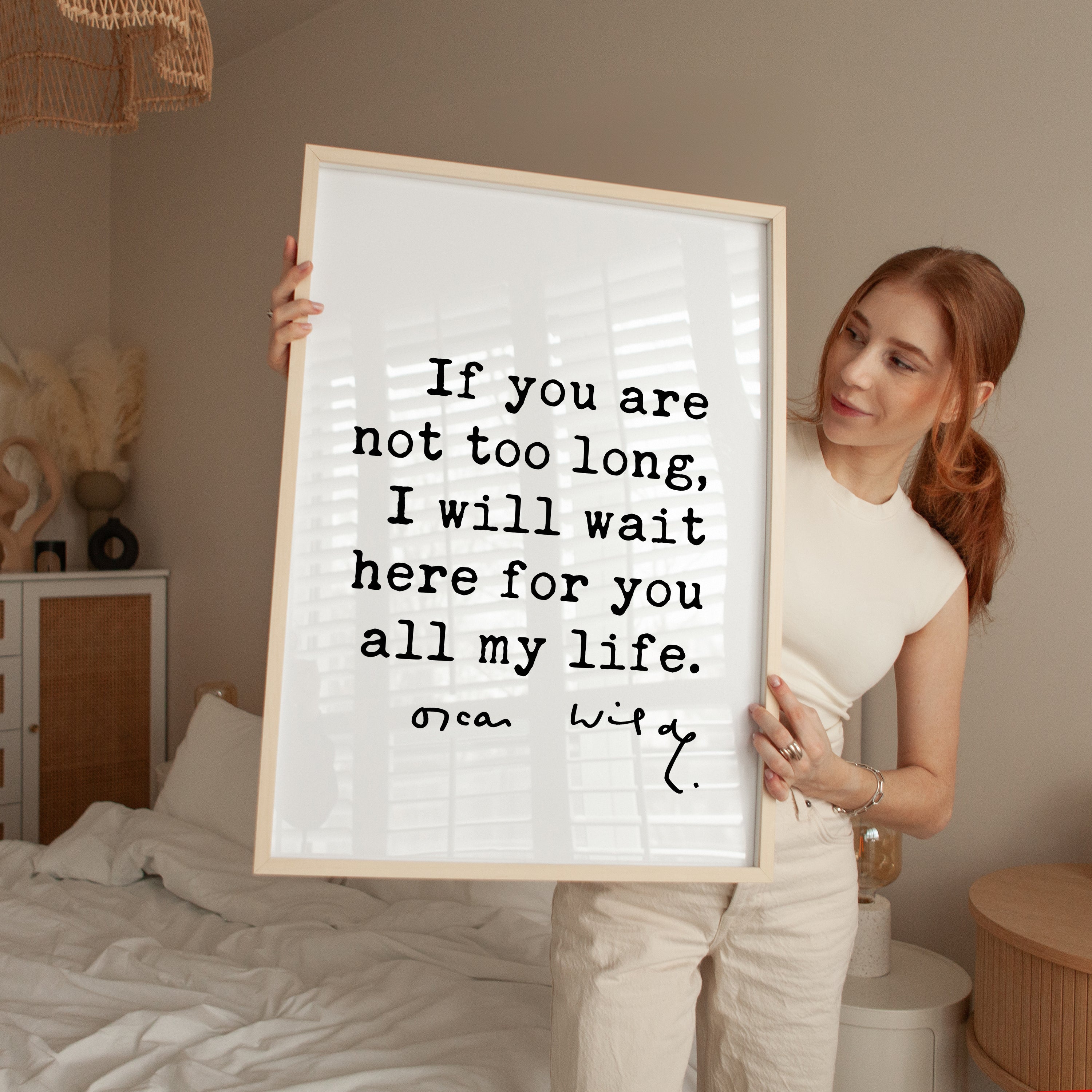 A woman holding a framed poster with a quote from Oscar Wilde.
