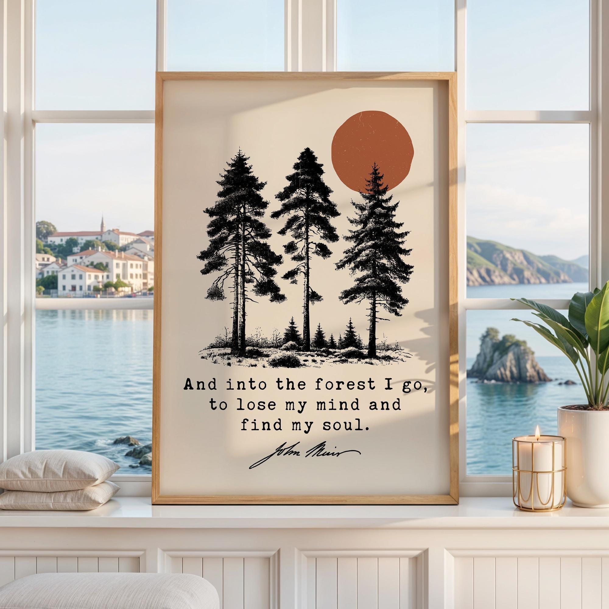 May include: A framed wall art print featuring a black ink illustration of three pine trees and a burnt orange sun against a cream background. The text reads, "And into the forest I go, to lose my mind and find my soul." with the signature John Muir.
