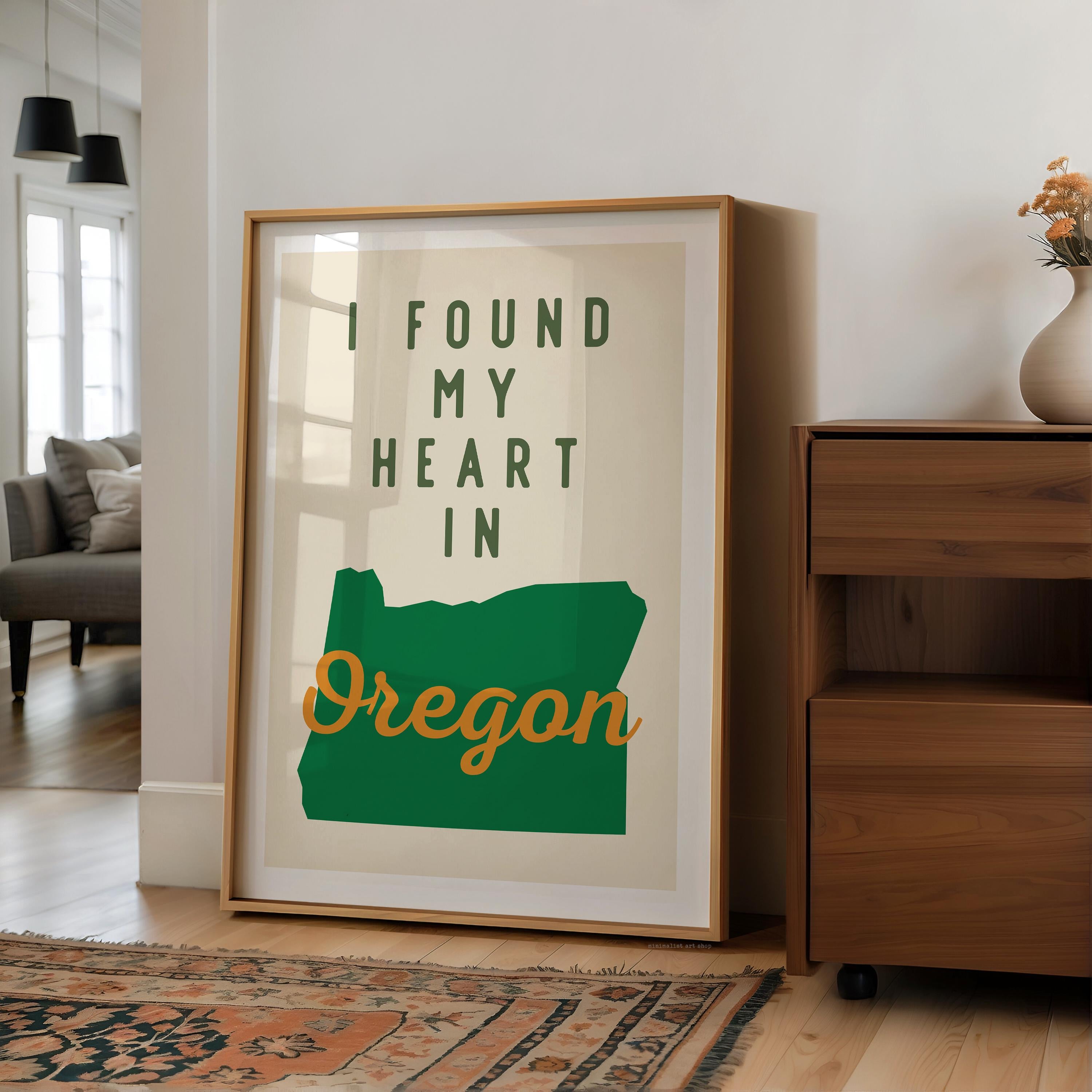 a framed poster with the text "I FOUND MY HEART IN OREGON" on it, placed on a wooden floor next to a dresser.