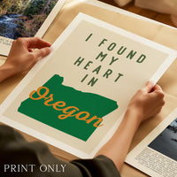 A person's hands are holding a framed print with the text "I FOUND MY HEART IN OREGON" and a graphic of the state of Oregon.