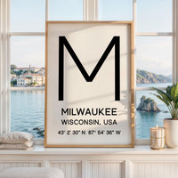 May include: A framed vertical wall art print featuring a large black letter M at the top. Below the letter, the text reads MILWAUKEE, WISCONSIN, USA, followed by the geographic coordinates 43° 2' 30" N 87° 54' 36" W in a clean, black sans-serif font.