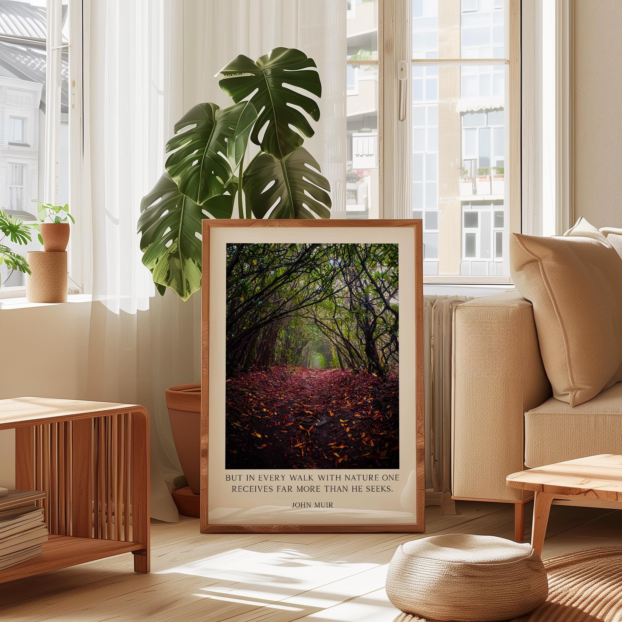 A framed photograph of a forest path with fallen leaves is displayed in a living room, accompanied by a quote about nature and the importance of walking with nature.