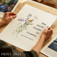 A person's hands are holding a printed poster with a floral design and a quote about the earth laughing at flowers.