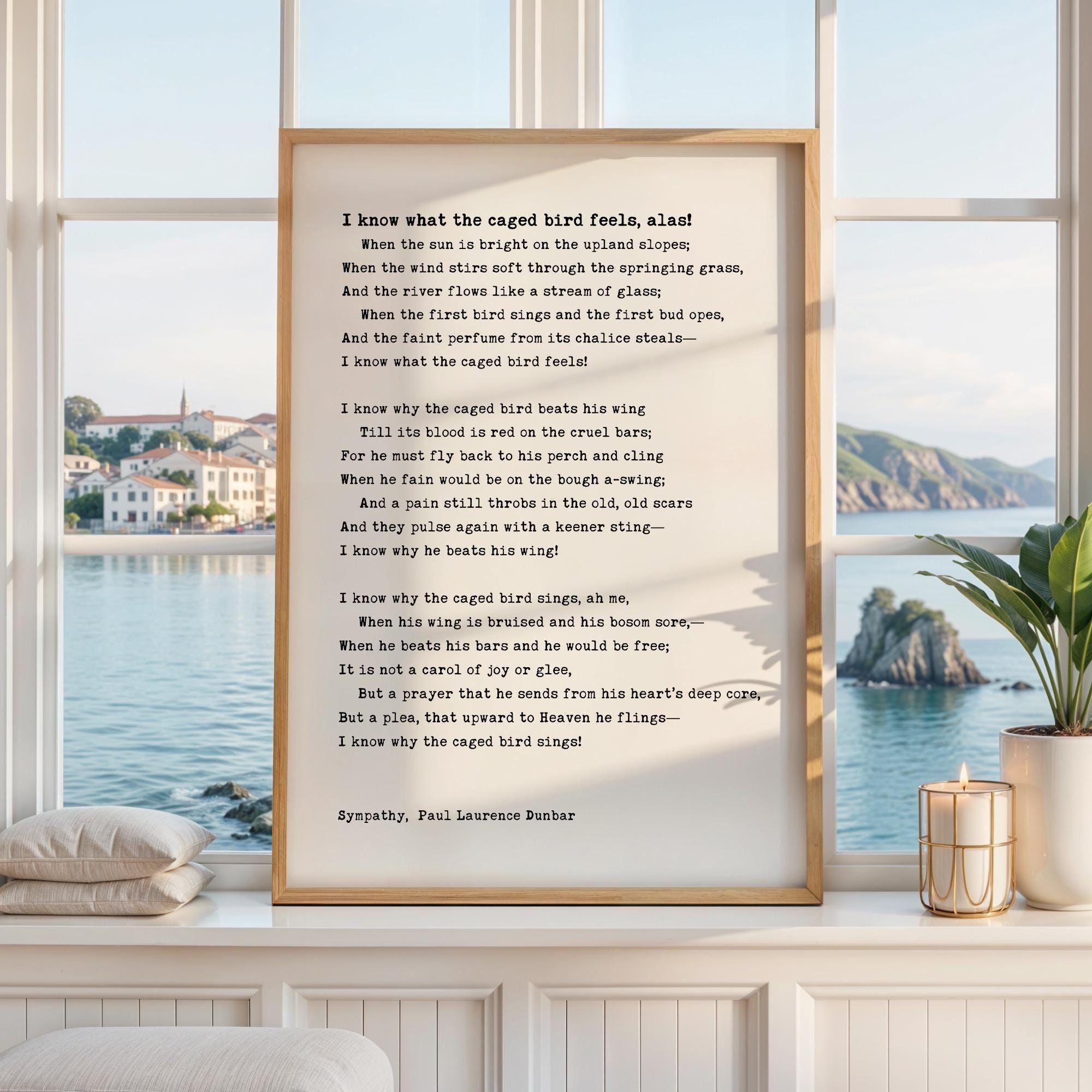 a framed poem titled "I know what the caged bird feels, alas" by Paul Laurence Dunbar, with a scenic view of a body of water and buildings in the background.
