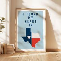 A framed poster with the text "I FOUND MY HEART IN" and a graphic of the state of Texas, with a stack of books and a plant to the side.