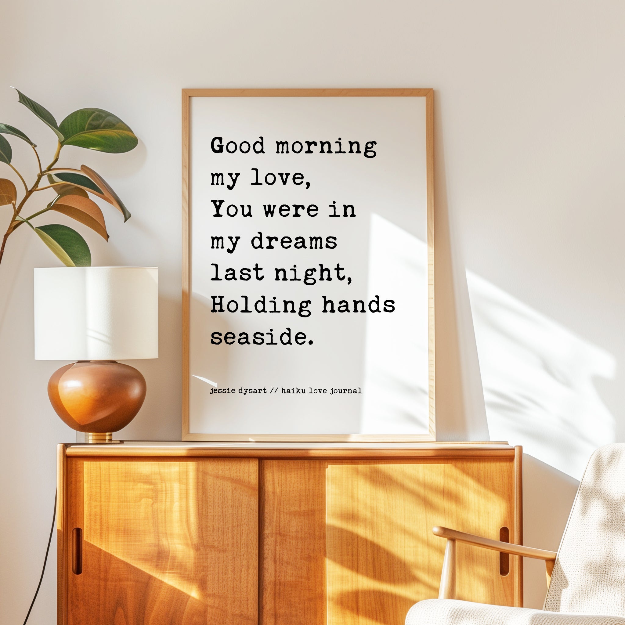 a wooden cabinet with a lamp on top, and a framed quote on the wall next to it.