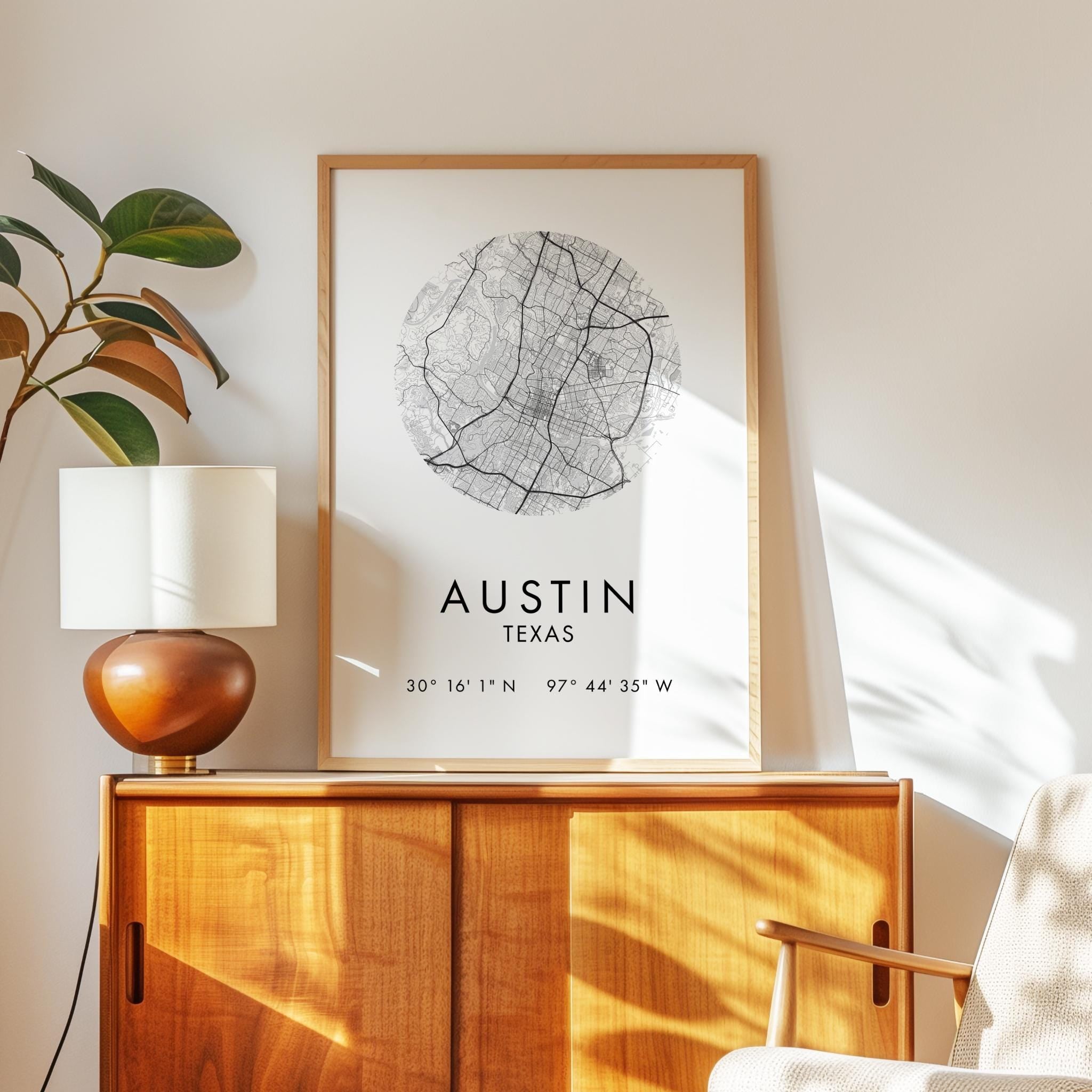 a framed map of Austin, Texas, with the city's location and coordinates displayed. The map is placed on a wooden cabinet, and there is a lamp and a plant nearby.