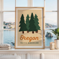May include: A rectangular wall art print in a light wood frame featuring a graphic illustration of four dark green pine trees against a beige background. The text Oregon is printed in a large orange script font above the text PACIFIC WONDERLAND.