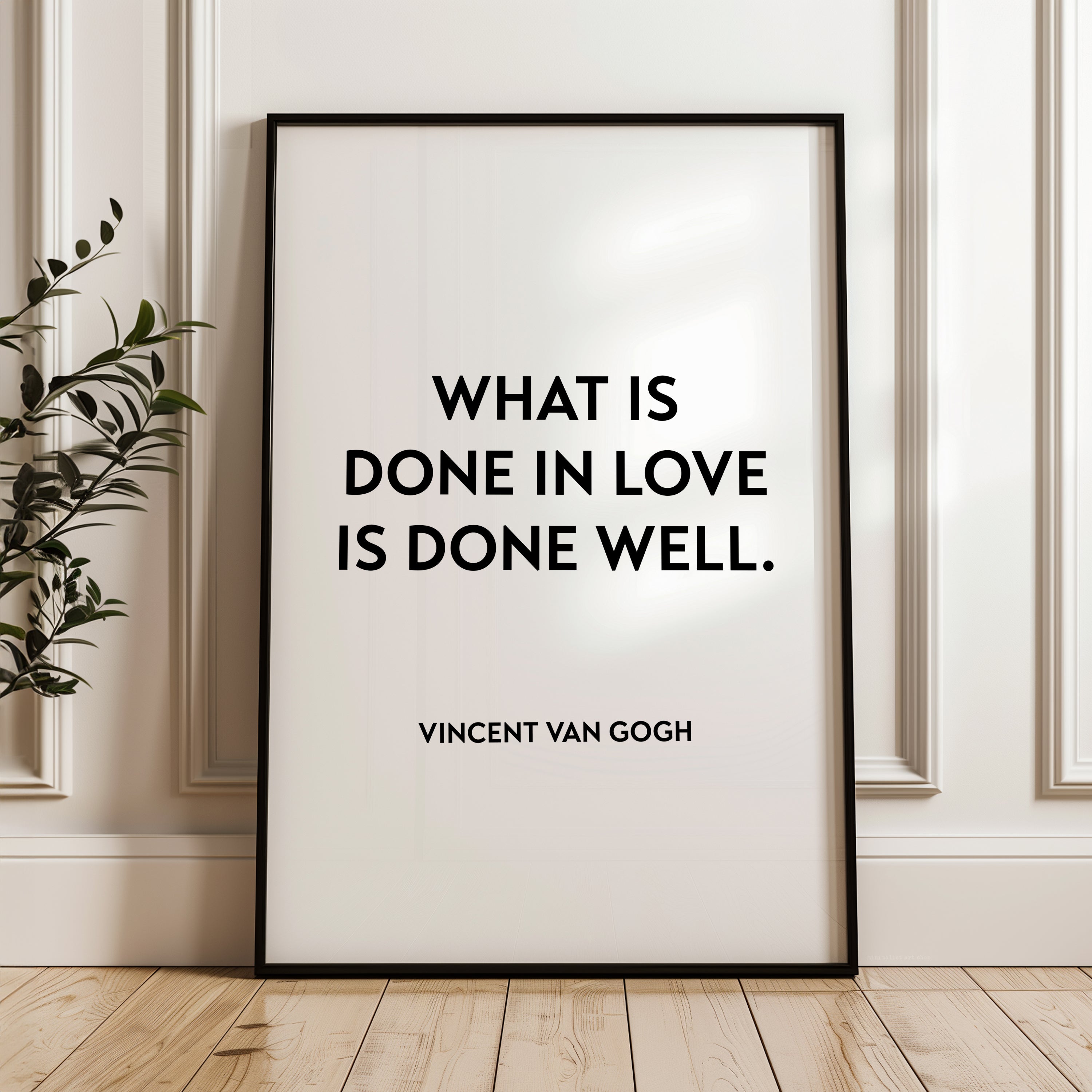 a quote by Vincent Van Gogh, "What is done in love is done well." The quote is displayed on a white poster frame, which is placed on a wooden floor against a white wall.