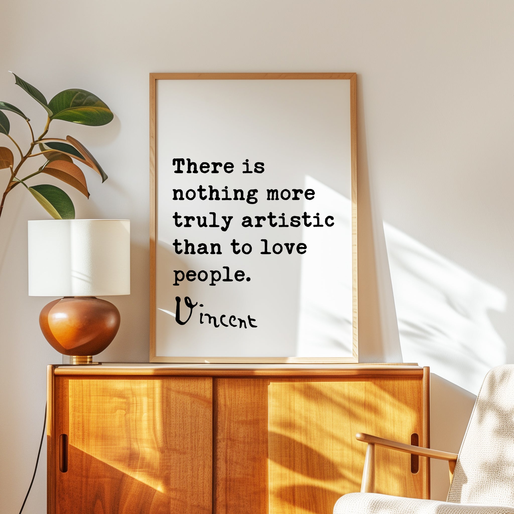 a framed quote by Vincent Van Gogh, which reads "There is nothing more truly artistic than to love people." The quote is displayed on a wooden cabinet or dresser, with a lamp and a plant nearby.