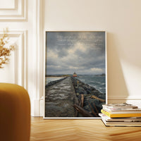 a painting of a lighthouse on a wall next to a stack of books