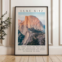 A framed poster of a mountain landscape with a Bible verse from Luke 6:12 overlaid on it.