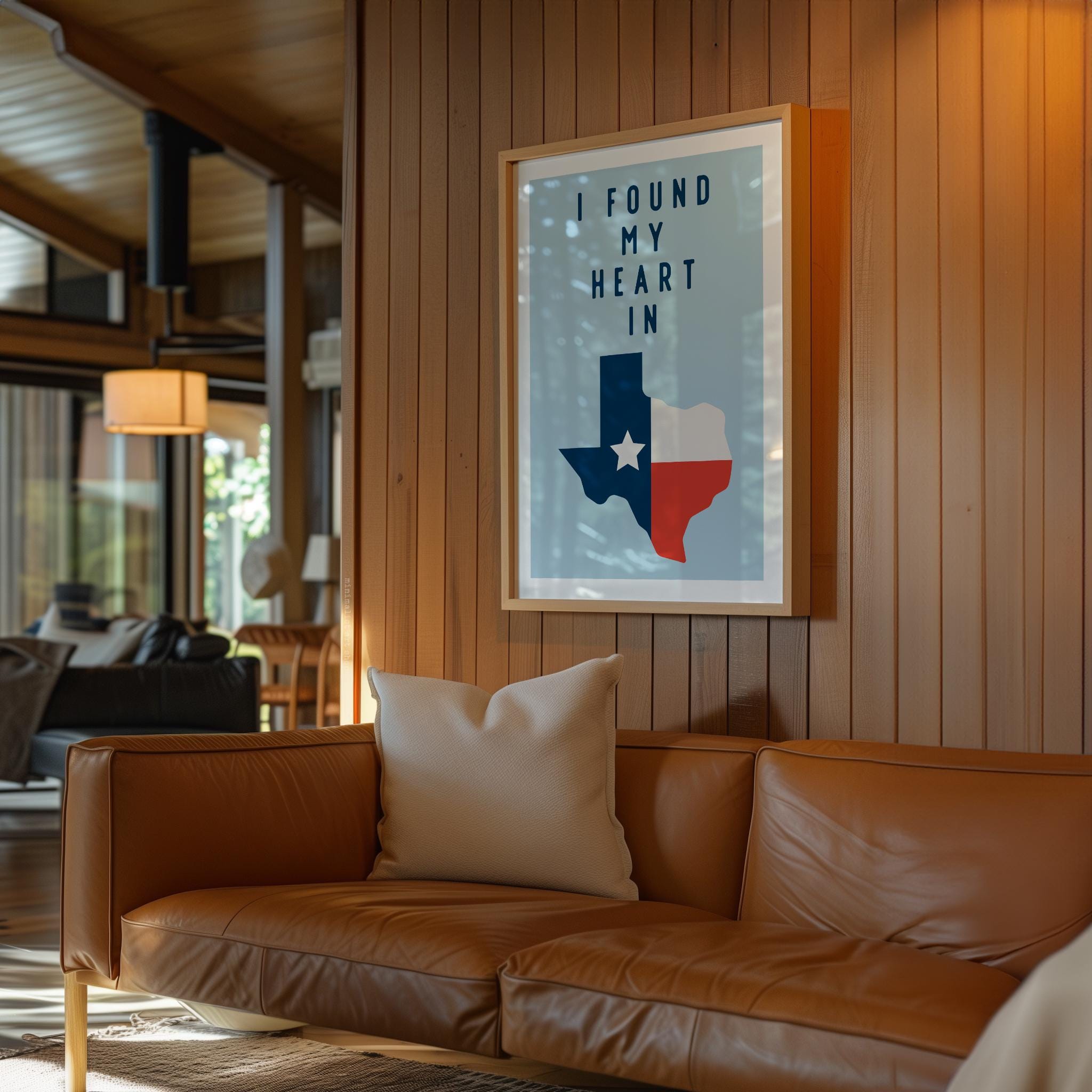 a cozy living room with a brown leather couch, a framed poster of the state of Texas, and a wooden wall.