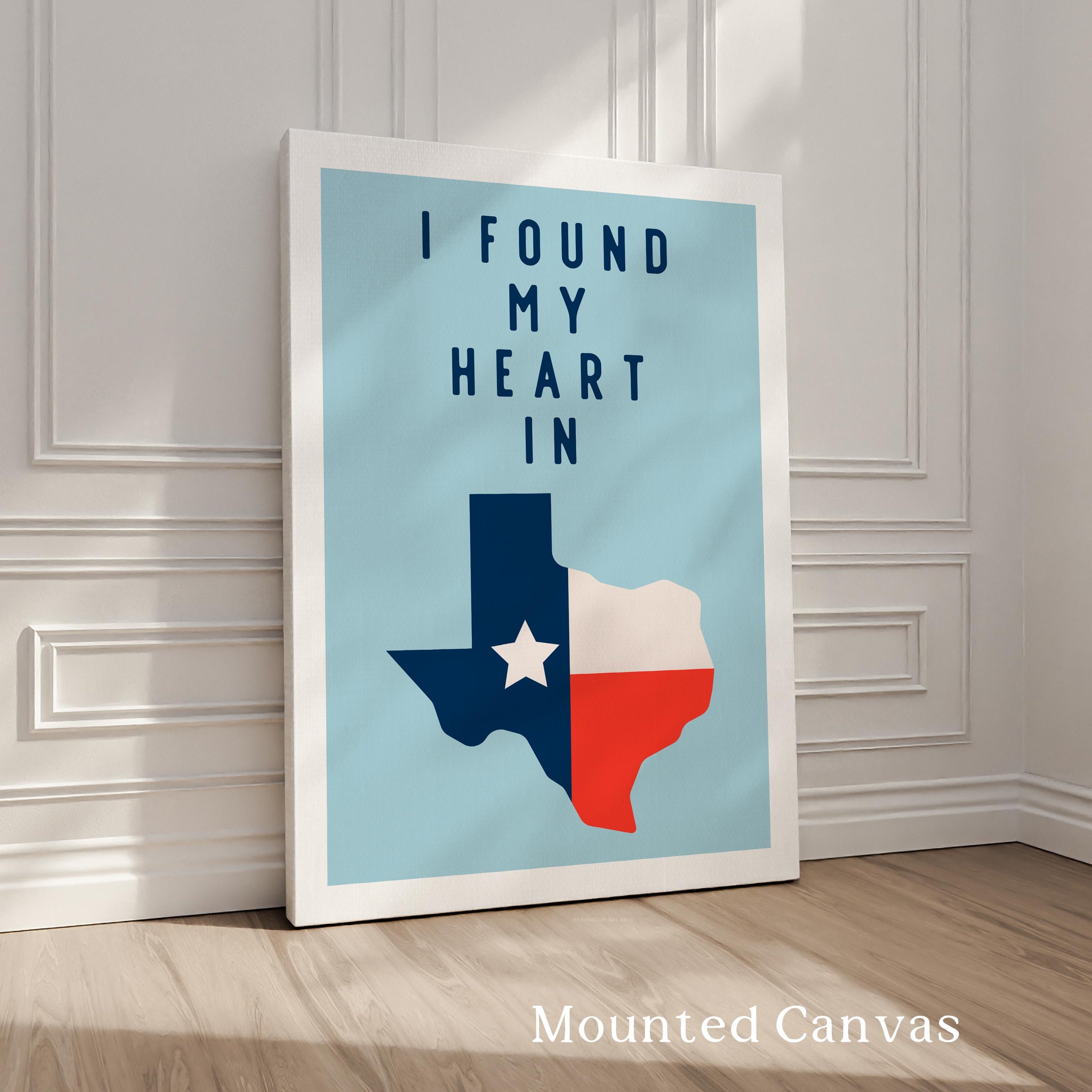 A framed poster with the text "I FOUND MY HEART IN" and a graphic of the state of Texas, standing on a wooden floor against a white wall.
